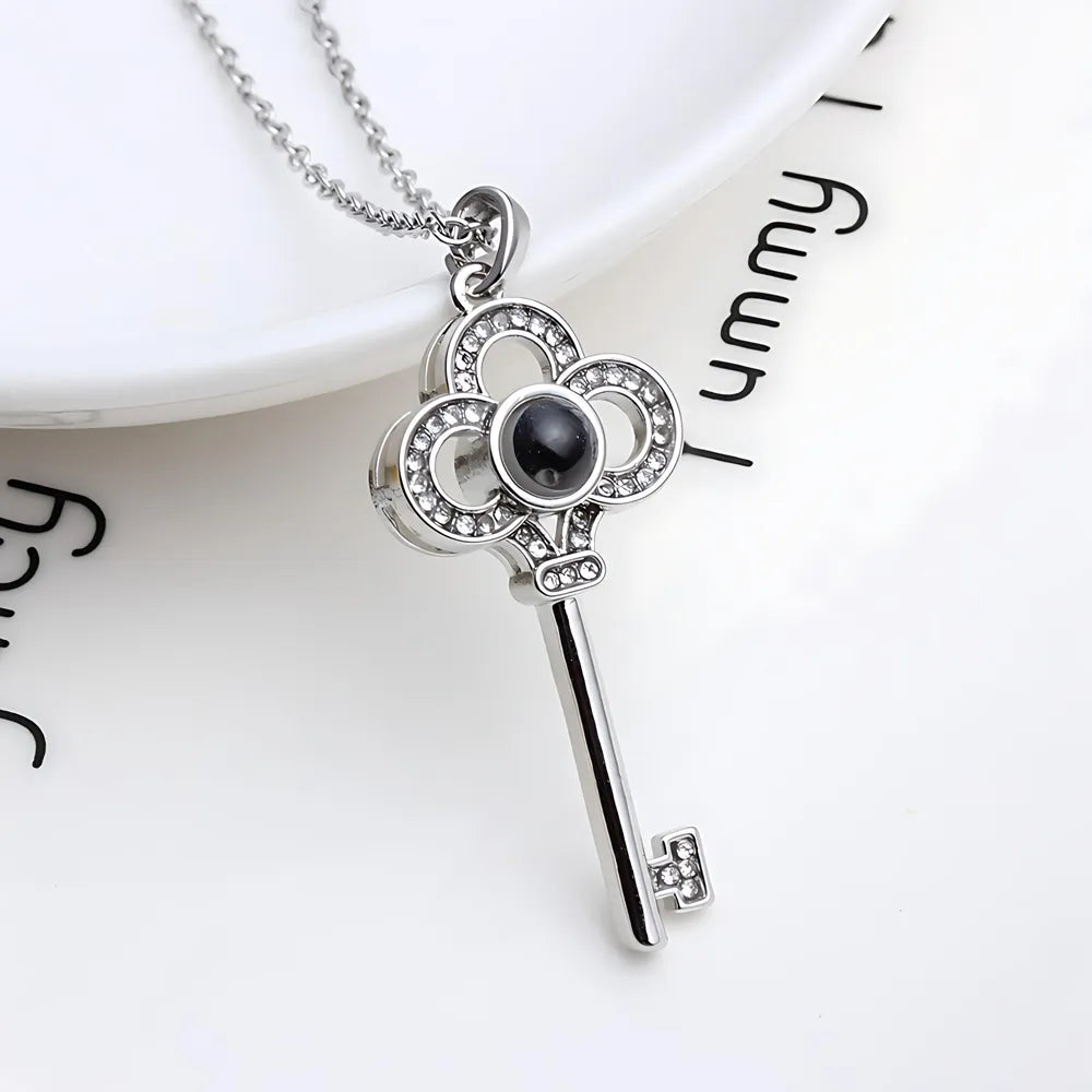 Silver key-shaped pendant with a black gemstone on a white background