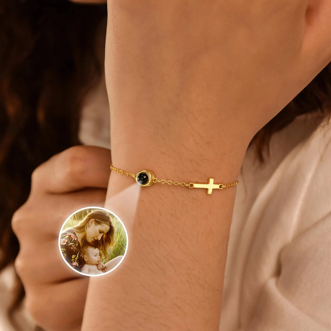 Gold bracelet with a black stone worn on a wrist, with a small inset showing a woman holding a child.
