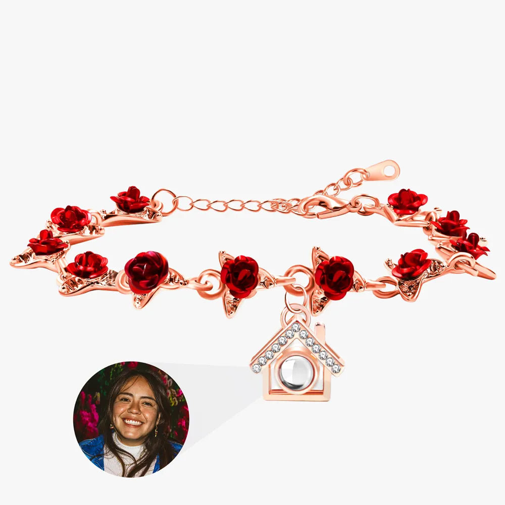 Rose gold bracelet with red floral charms and a house charm on a white background