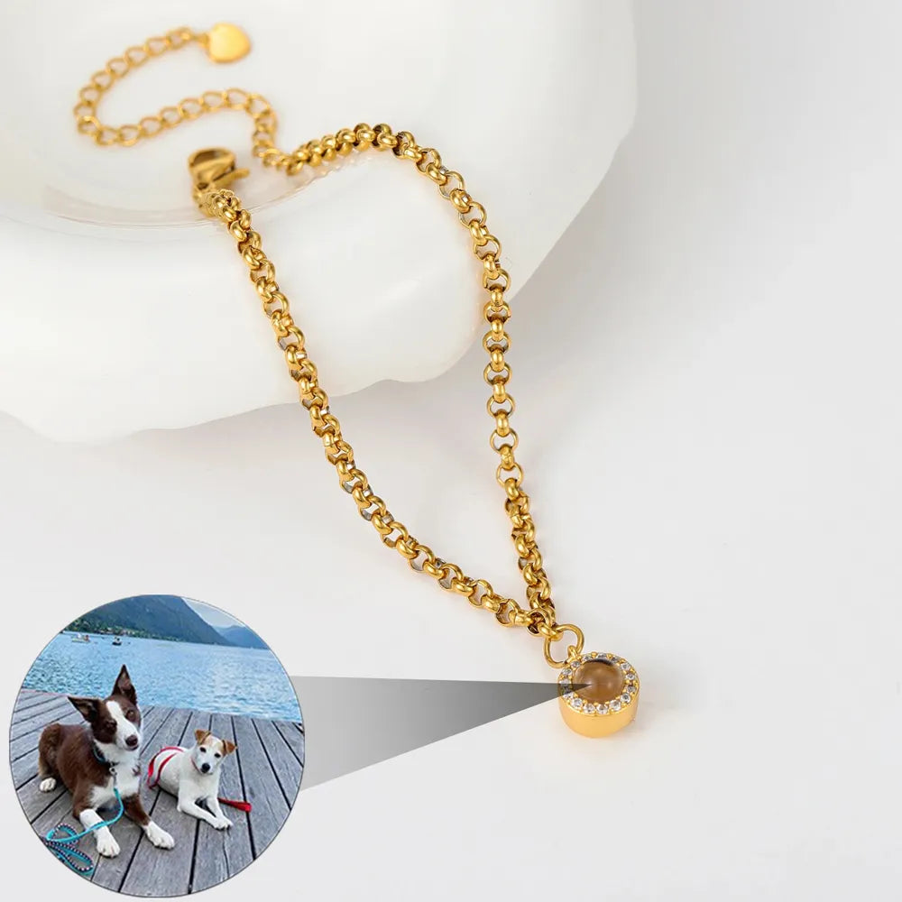 Gold chain necklace with a round pendant on a white surface.