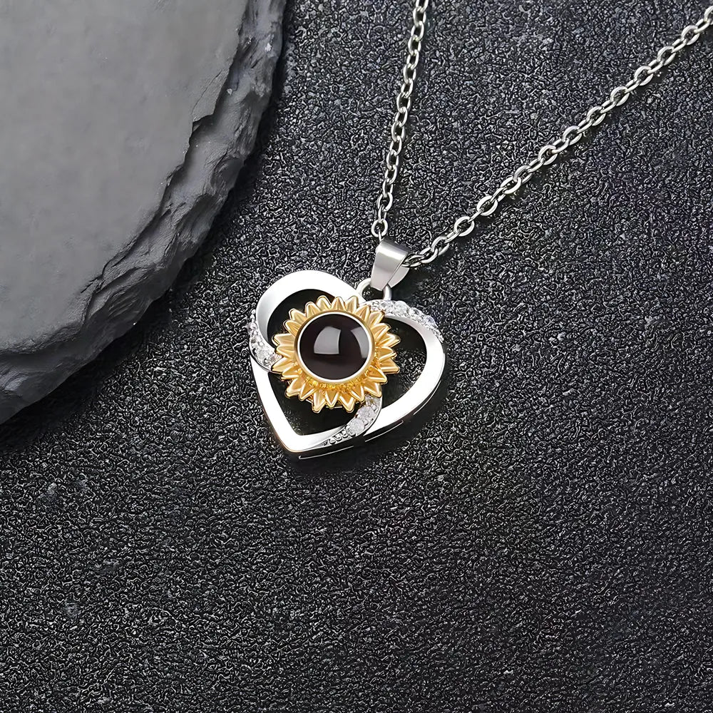 Heart-shaped pendant with sunflower design on a dark surface