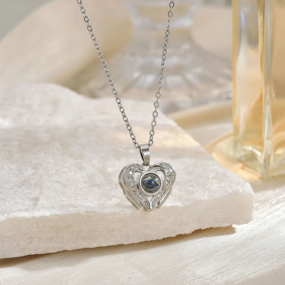 Silver heart-shaped necklace with a gemstone on a white fabric background